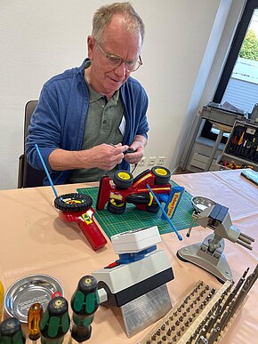 Ein Mitarbeiter des Repair-Café werkelt an einem ferngesteuerten Auto. 