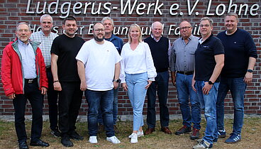 Eine Gruppe Leute vor dem Schriftzug des Ludgerus-Werk e.V. Lohne. 