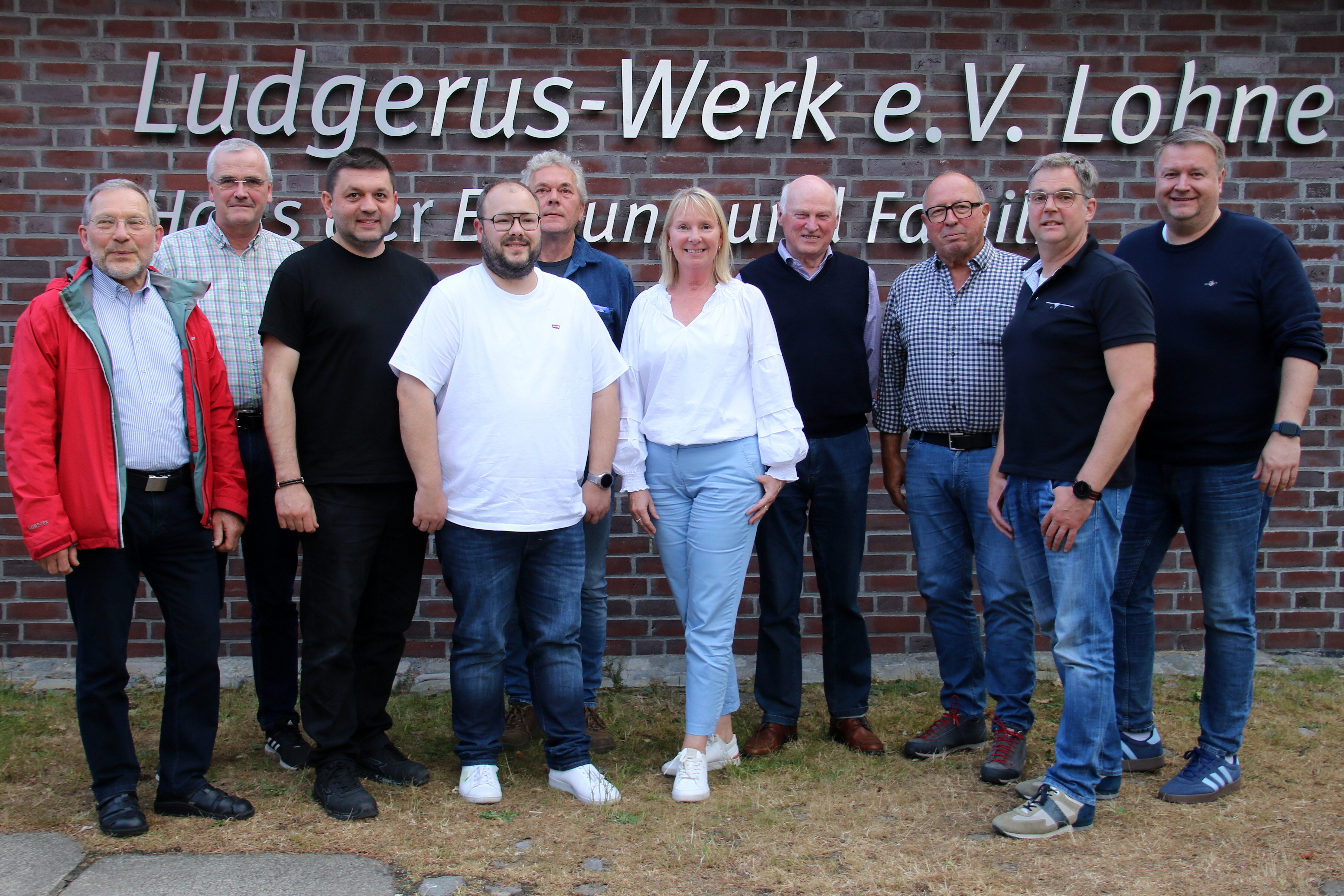 Eine Gruppe Leute vor dem Schriftzug des Ludgerus-Werk e.V. Lohne. 