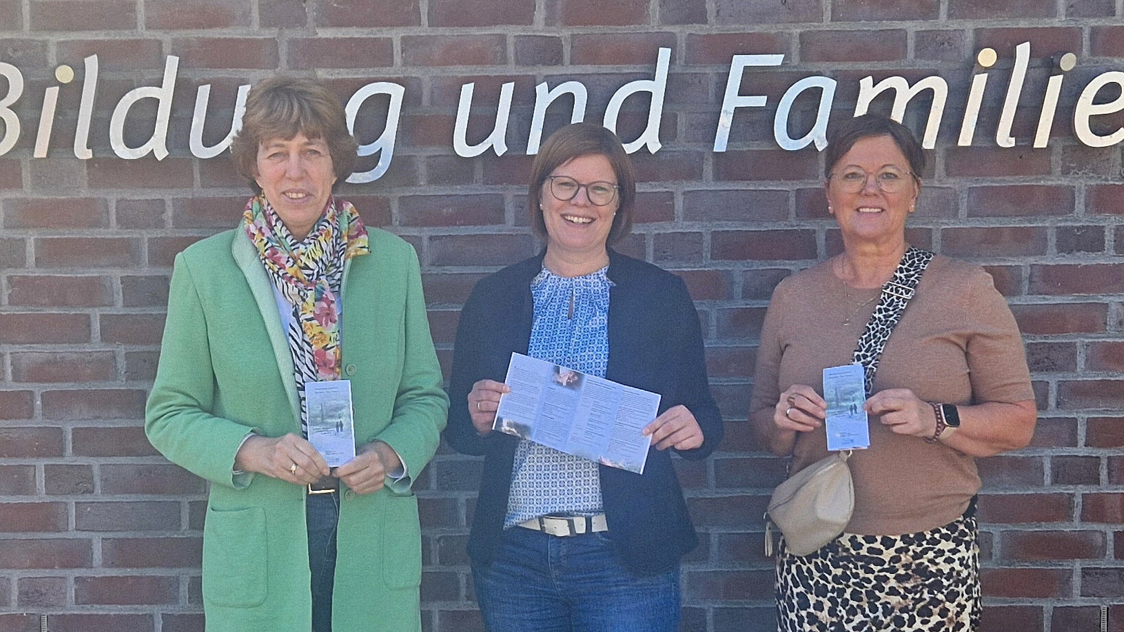 Die drei Initiatorinnen stehen vor dem Schriftzug vor dem Ludgerus-Werk und halten den Flyer zu der Veranstaltungsreihe in den Händen.