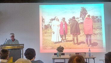 Die Dozentin Prof. Dr. Aka steht vor ihrer Präsentation über die Missionarinnen. Davor sitzen die Zuhörenden des Vortrags.