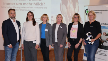 Eine Gruppe Leute in stehen vor der Leinwand in der Hofstelle im Ludgerus-Werk. Die Person, die ganz rechts steht, hält eine Stoffkuh in den Händen. 
