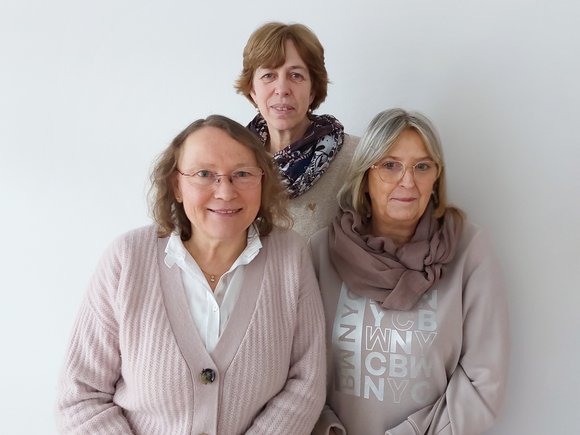 Das Team des Seniorentreffpunkts steht vor einer weißen Wand. 